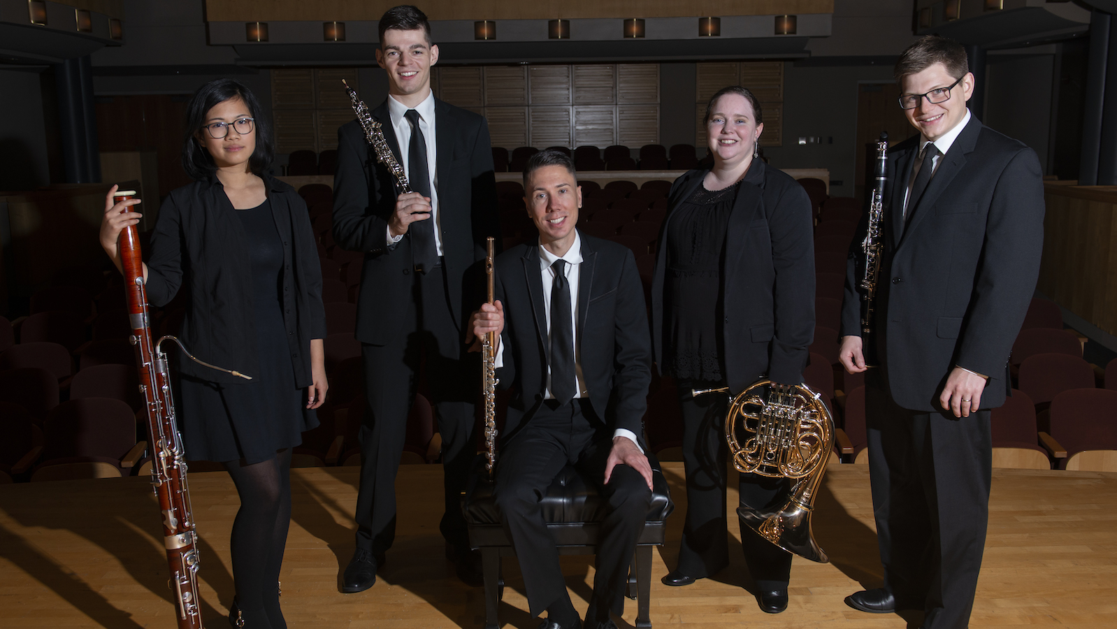  Woodwind quintet members holding instruments.