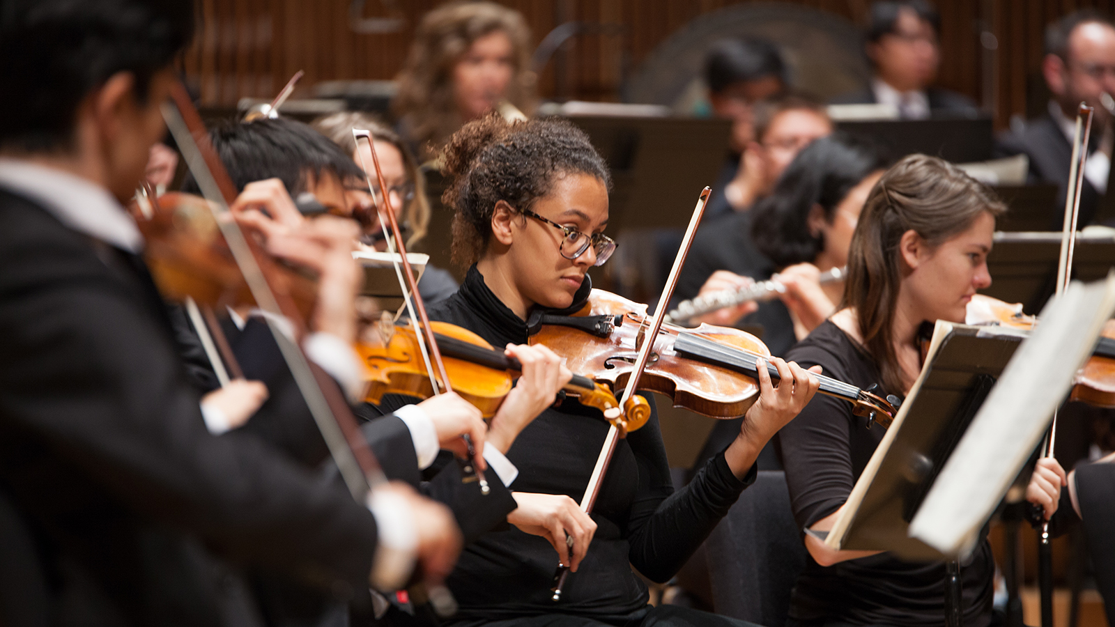 A close-up shot of violinists performing in an orchestra.
