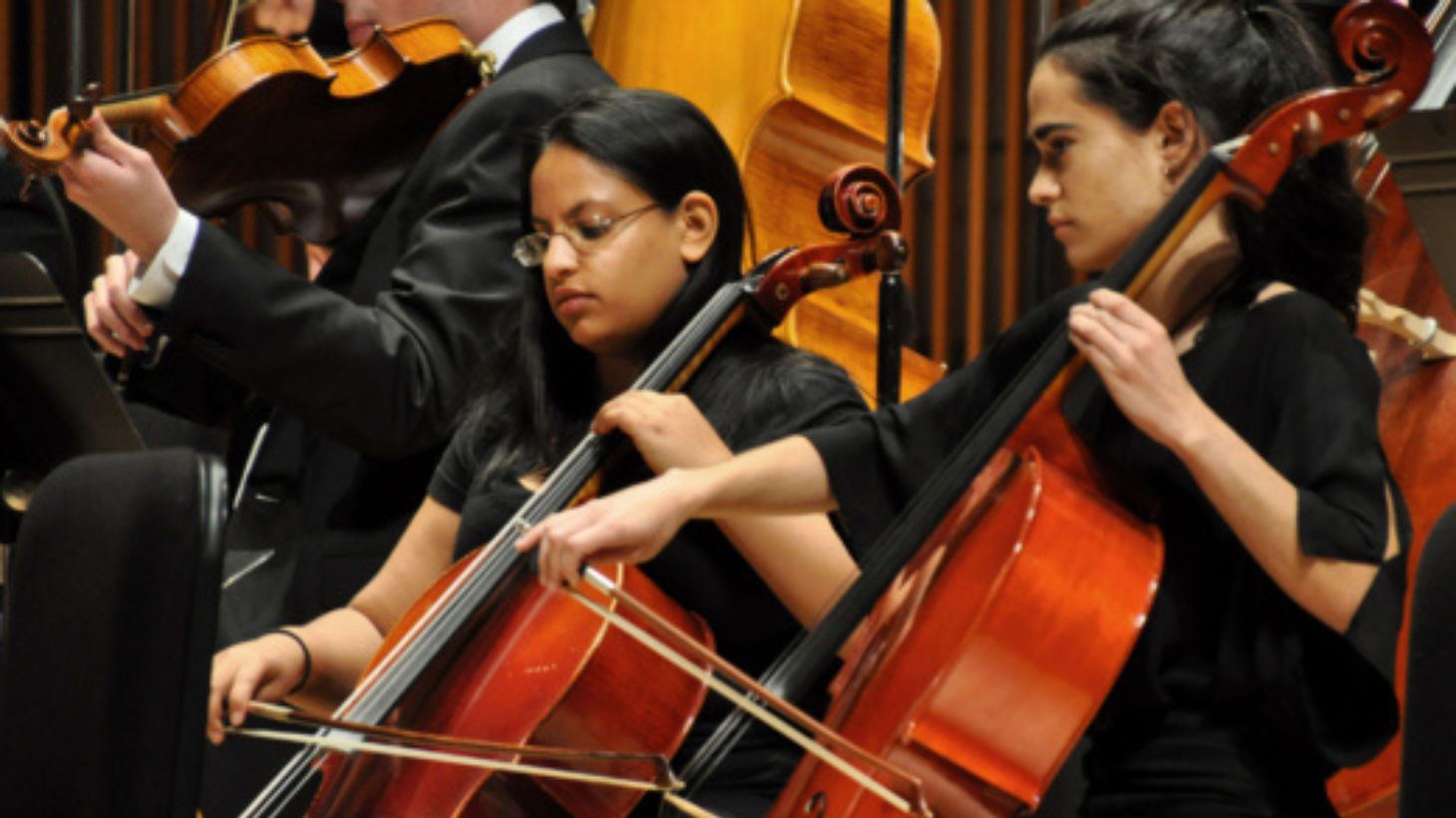 Students play cellos on stage.