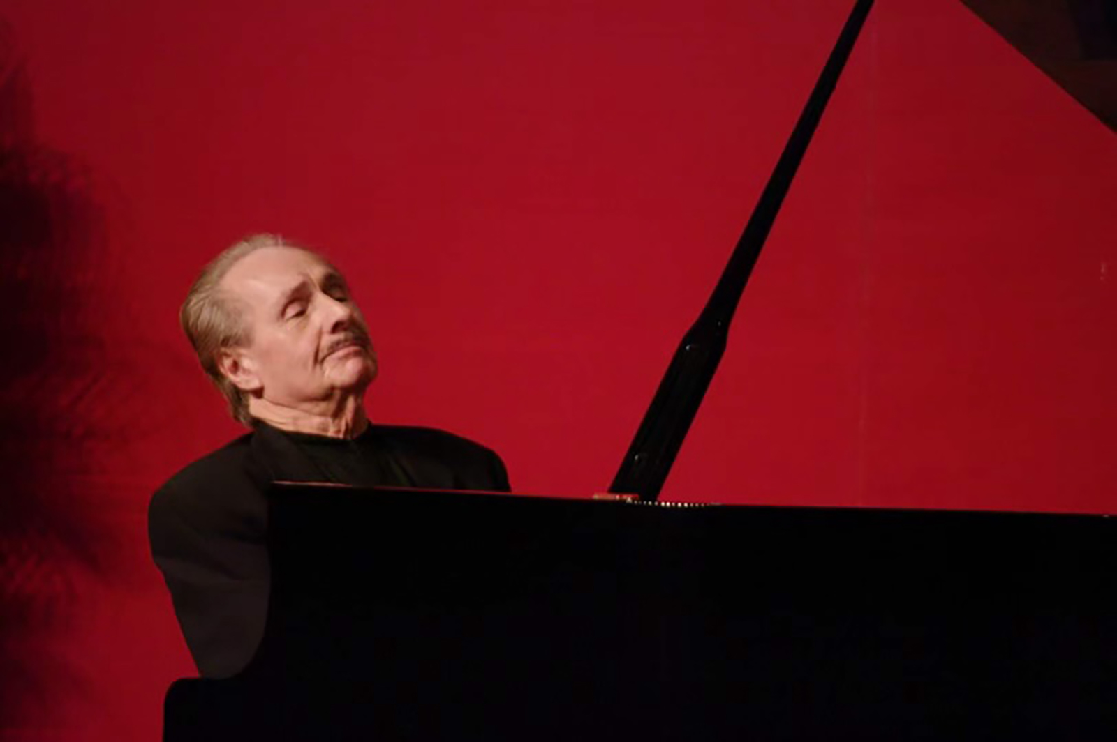 Thomas Schumacher playing a piano against a red background