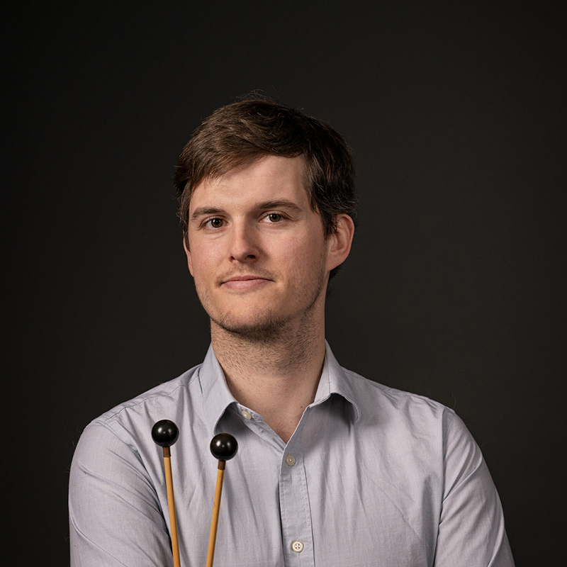 Edouard Beyens. He has his arms folded across his chest and he is holding mallets against his chest.