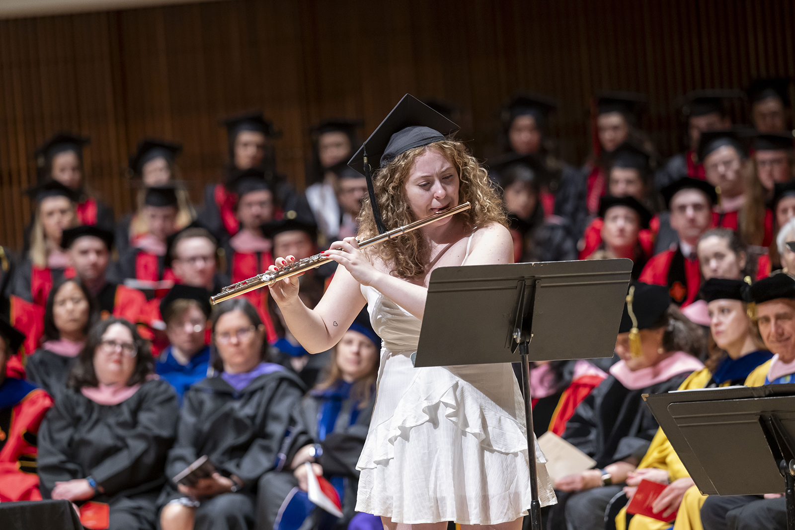 A student in a graduation cap plays flute.
