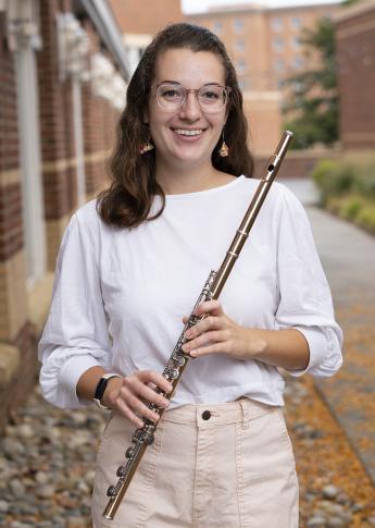 Jeanette-Marie Lewis, wearing a white blouse, poses for a photo with her flute.
